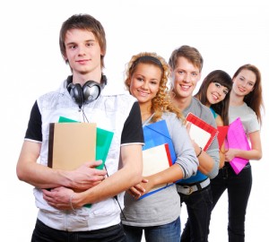 Group of  young  joyful students standing with book and bags